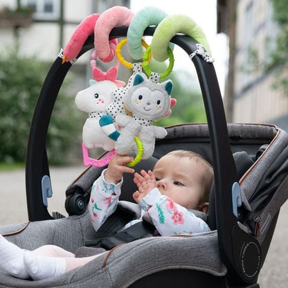Dziecko w foteliku pod spiralą Fehn Aiko i Yuki, dotykające zawieszki kotka.