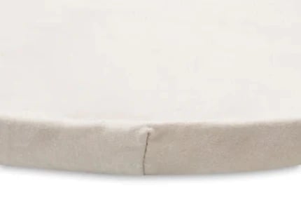 Zbliżenie na jasnobrązową powierzchnię prześcieradła i szew przy jego krawędzi.