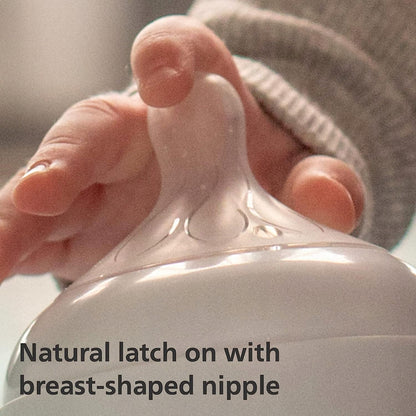 Dłoń dotykająca przezroczystego smoczka Philips Avent Natural Response na białej butelce.